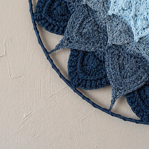 Close-up of a blue and gray crocheted fabric on a beige surface