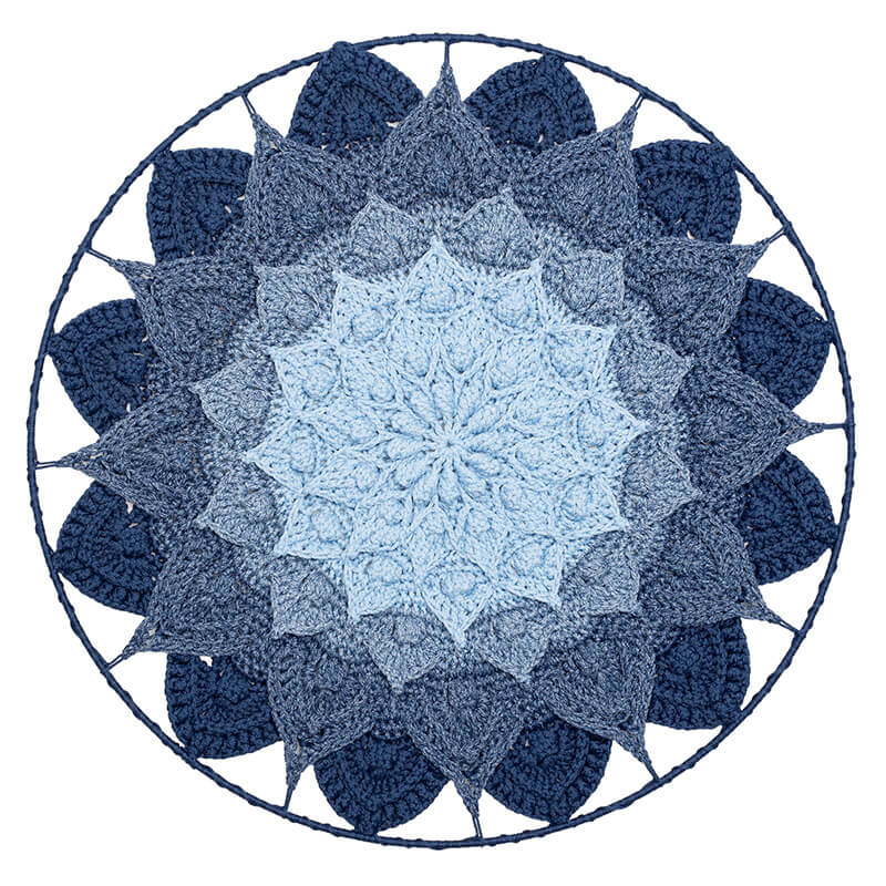 Crocheted mandala with a gradient of blue colors on a white background