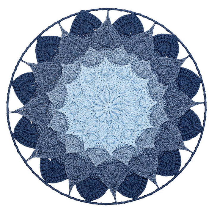 Crocheted mandala with a gradient of blue colors on a white background