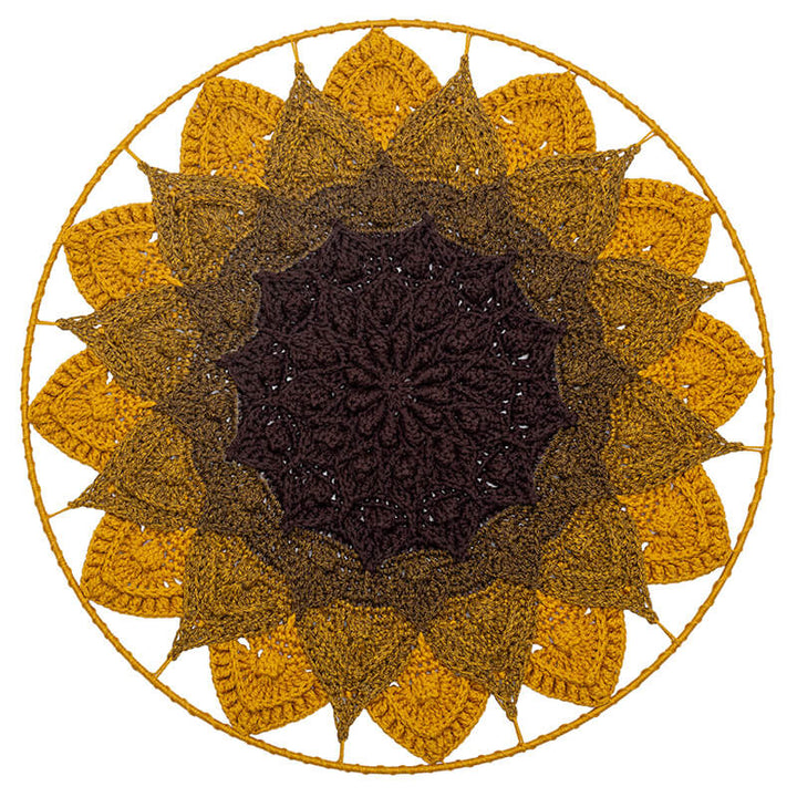 Round crochet wall hanging with sunflower design in brown and yellow on a white background