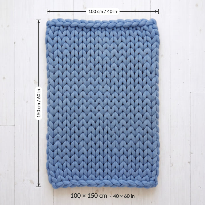 Chunky knit throw blanket size 100 x 150 cm (40 x 60 in), laid flat on a white wooden floor