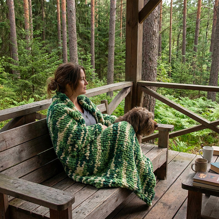 lady wrapped in multicolor green and yellow chunky chenille blanket in the woods in the patio