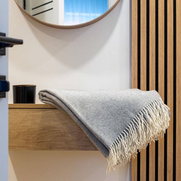 light gray woven merino throw folded on a shelf