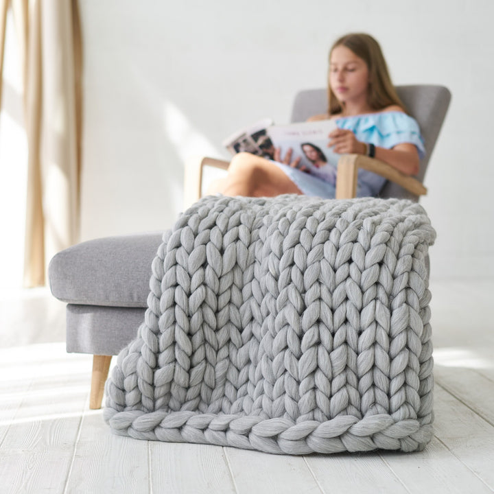Plaid grosse maille gris clair posé sur un fauteuil