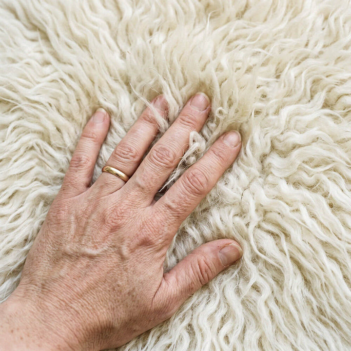 Hand with a gold ring on a fluffy white surface