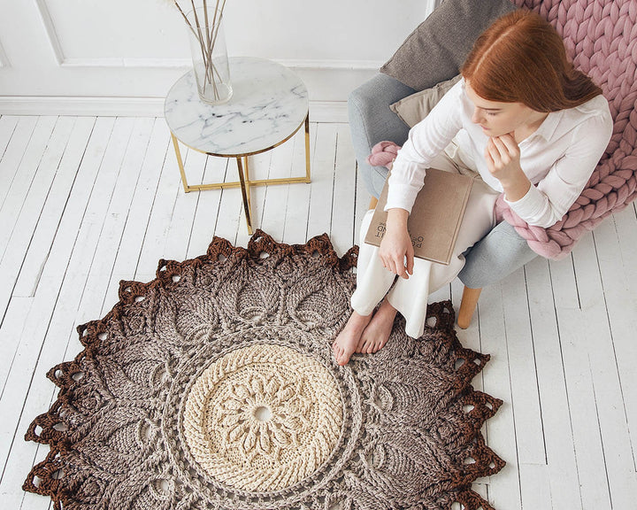 Woman sitting on a textured rug in a room with a marble side table.