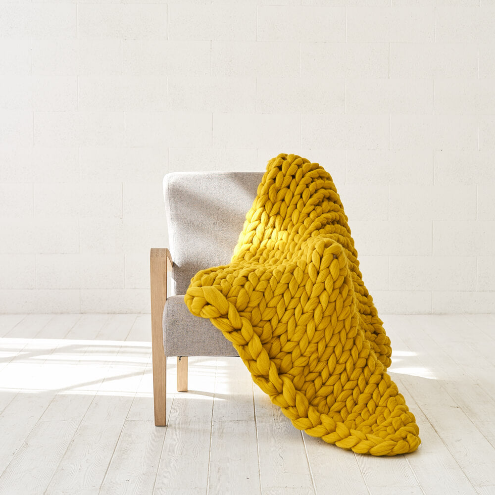 mustard chunky knit blanket on the grey chair