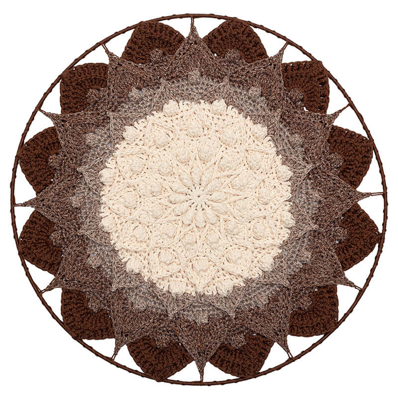Round crochet doily with a white center and brown outer petals on a white background