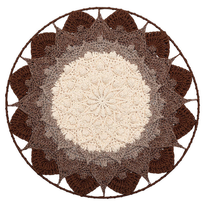 Round crochet doily with a white center and brown outer petals on a white background