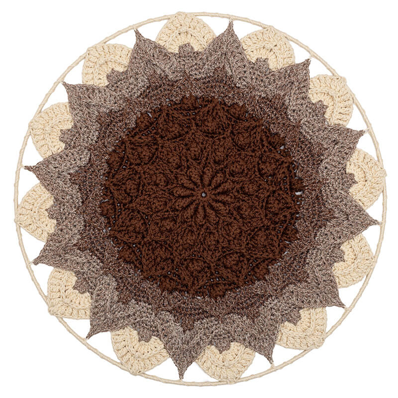 Round crochet wall hanging with a brown center and beige border on a white background