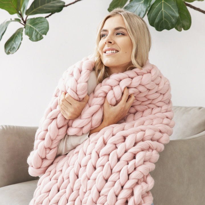 Femme enveloppée dans un plaid grosse maille rose en laine mérinos
