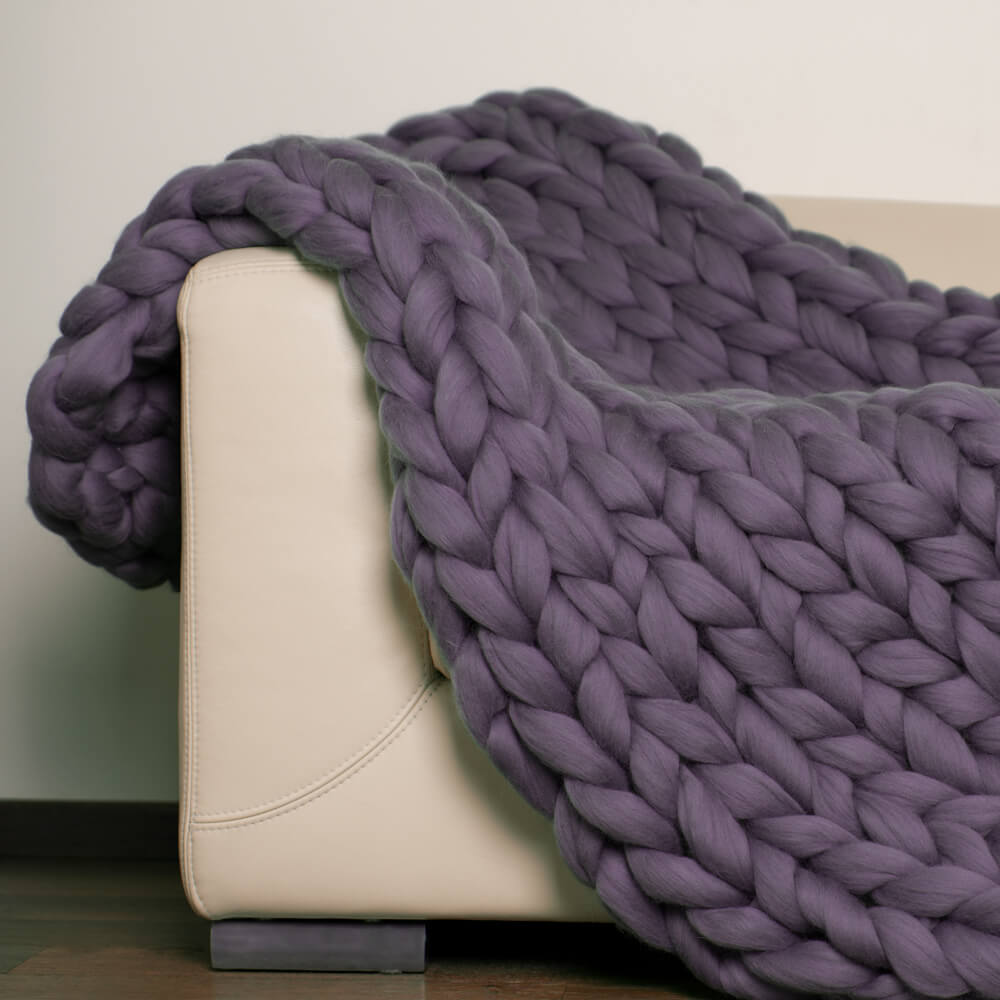 purple chunky knit throw draped over beige armchair