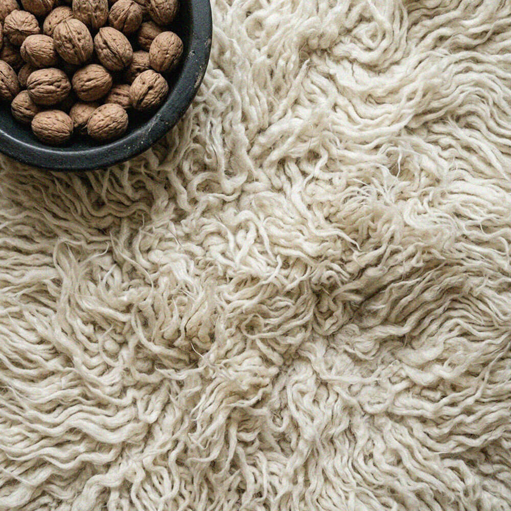 Close-up of a textured beige surface with a bowl of walnuts.