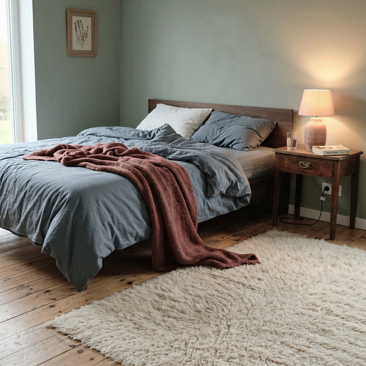 Bedroom with a bed, nightstand, and lamp in a cozy setting.