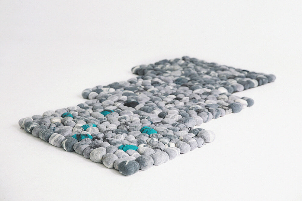 a small handmade felted wool pebbles rug in gray on the floor