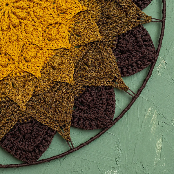 Crocheted fabric with leaf patterns in yellow, brown, and purple on a green background