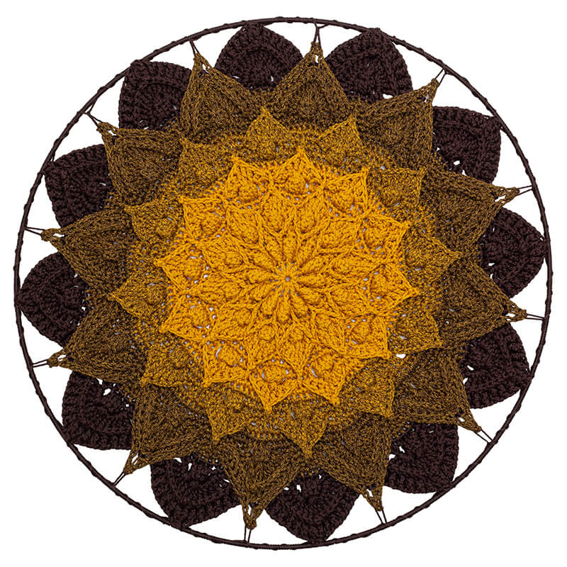 Crocheted mandala with a yellow center and brown outer petals on a white background