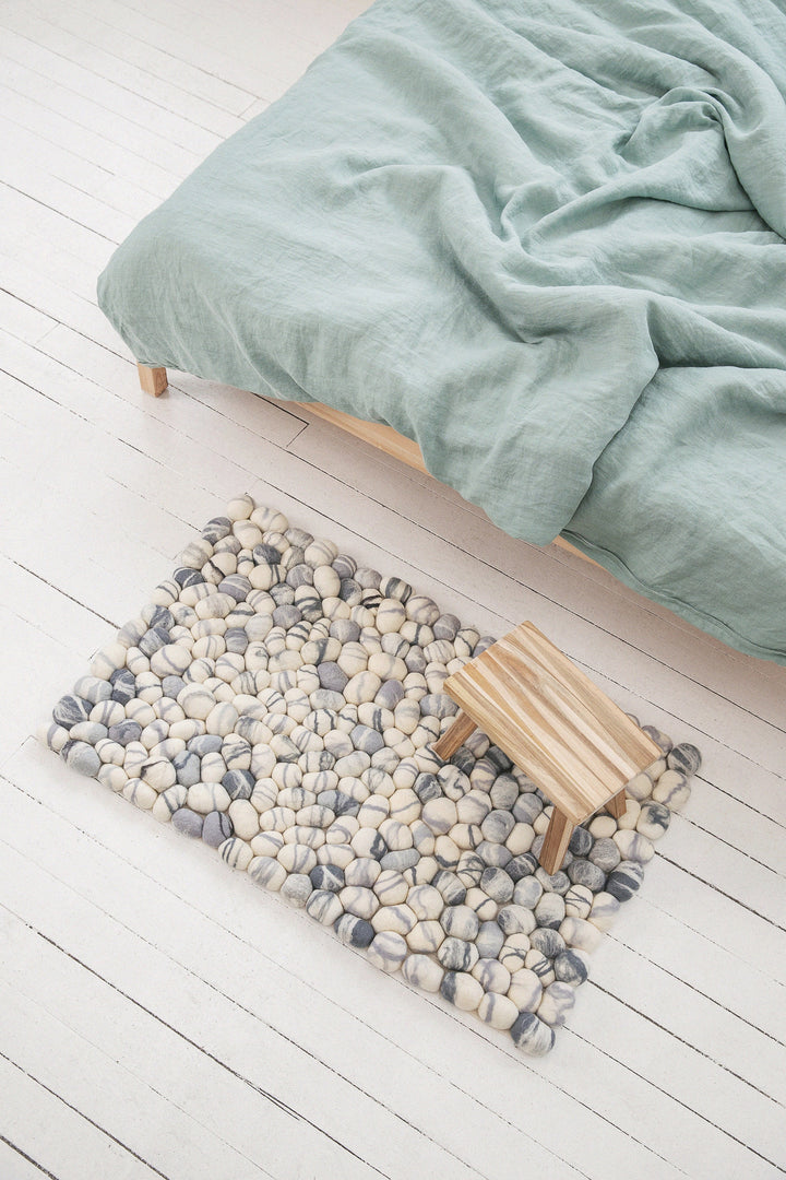 white with grey elements felted wool pebbles rug from the top at the bed with green bedding